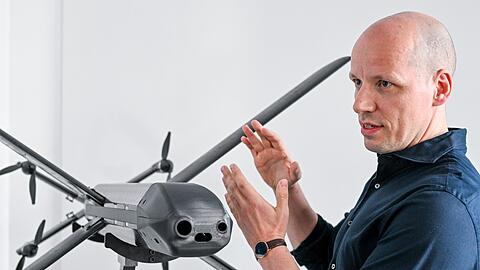 Ein Modell der HX-2-Drohne von Helsing, daneben der Mitgründer und Co-Firmenchef Gundbert Scherf.