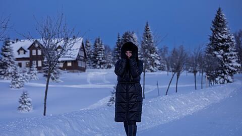 Eine Frau spaziert durch eine verschneite Landschaft in Tschechien.