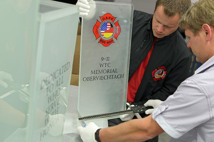 Der Glasbearbeiter Sandro Kramer (rechts) und der 2. Vorstand der "German American Firefighters and Friends", Oliver Süß, vermessen ein Glaselement des Denkmals für den 11. September 2001 der Gemeinde Oberviechtach.