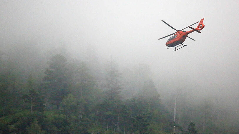 Ein Rettungshubschrauber sucht bei Nebel und Regen nach dem verirrten Bergwanderer.