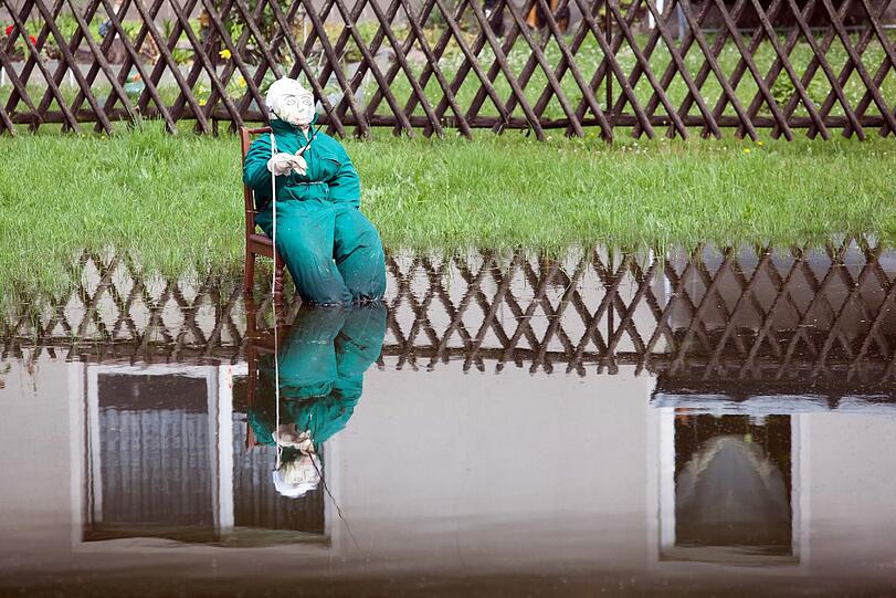 Wasserscheuche? Eine als Angler kostümierte lebensgrosse Puppe sitzt in Mödlich bei Dömitz (Mecklenburg-Vorpommern)in einer Wiese.