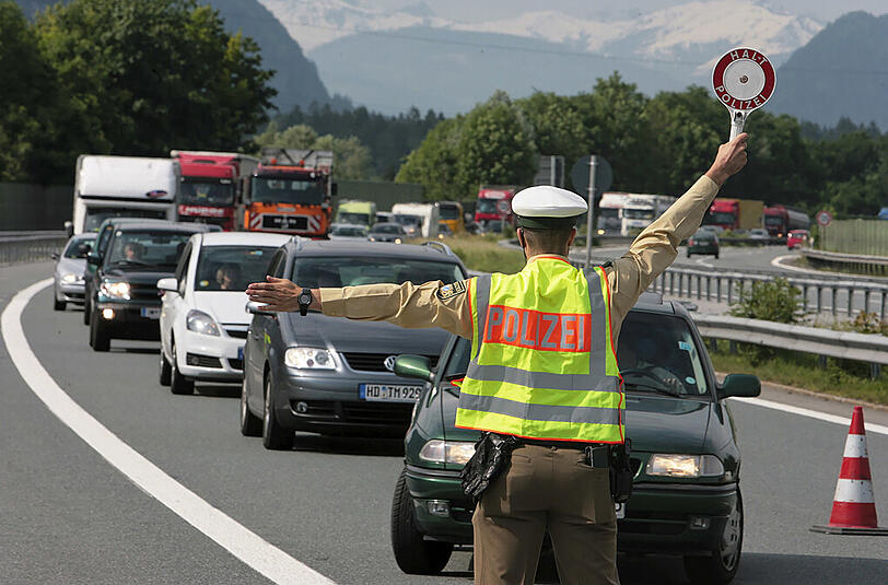 Ein Polizist winkt am österreichisch-deutschen Autobahn-Grenzübergang Kiefersfelden Autos von der Straße (Archivbild).