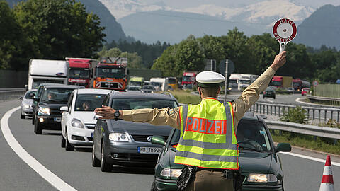 Ein Polizist winkt am österreichisch-deutschen Autobahn-Grenzübergang Kiefersfelden Autos von der Straße (Archivbild).