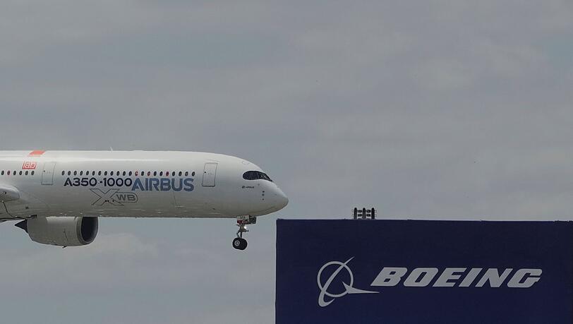 Die zwei großen Konkurrenten: Ein Airbus fliegt bei einer Vorführung auf der Luftfahrtmesse Salon du Bourget an einem Logo von Boeing vorbei.