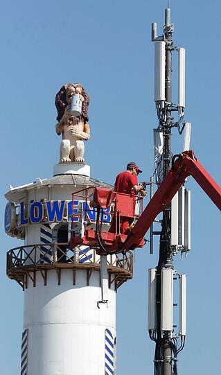 Damit man auf der Wiesn alle seine Freunde findet, muss unbedingt das Handy mit. Deswegen werden hier schon mal Mobilfunkantennen montiert... Der Brauerei-Löwe schaut gelassen zu und leert schon mal die erste Maß.
