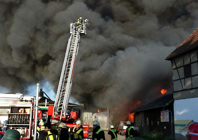 Feuerwehrleute löschen am Sonntag in Lichtenfels (Oberfranken) einen Brand von vier Hallen in einem Industriegebiet, bei dem ein hoher Schaden entstanden ist.
