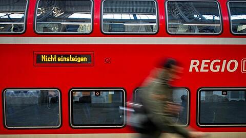 Ein Fahrgast läuft an einer Regionalbahn der Deutschen Bahn vorbei. Foto: Christoph Schmidt/dpa/Archivbild