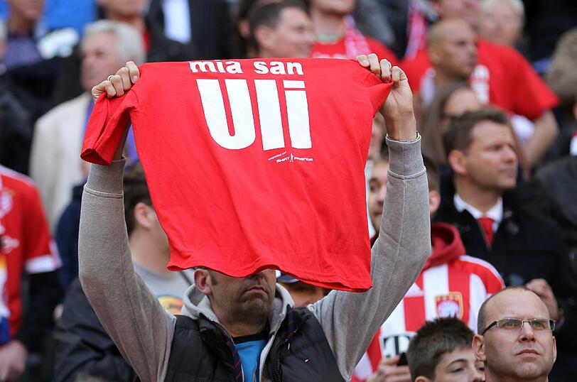 "Mia san Uli"-Schriftzüge auf T-Shirts und Plakaten in der Arena.