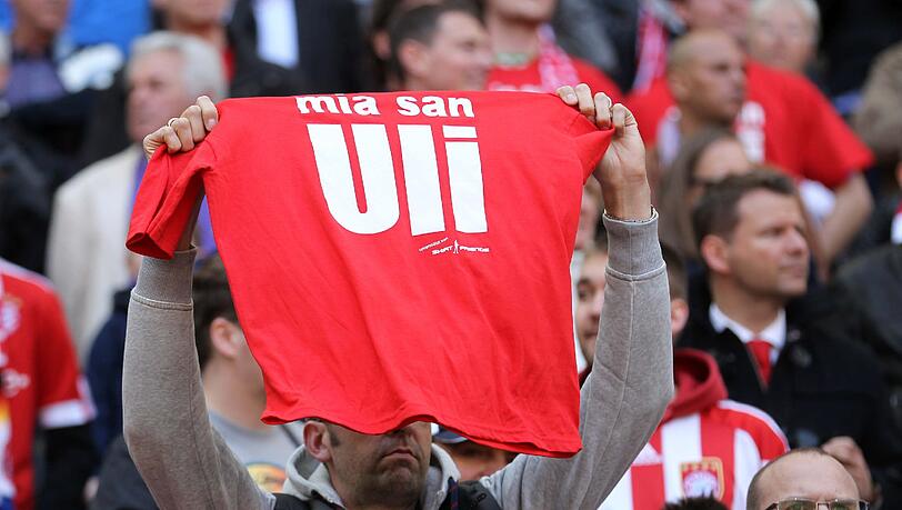 "Mia san Uli"-Schriftzüge auf T-Shirts und Plakaten in der Arena. "Mia san Uli"-Schriftzüge auf T-Shirts und Plakaten in der Arena.