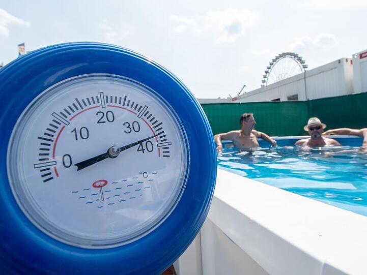 Im bayerischen Straubing zeigt ein Thermometer schon 38 Grad an, während sich die Monteure eines Messestands für Pools während einer Pause auf dem Gelände der Ostbayernschau abkühlen.