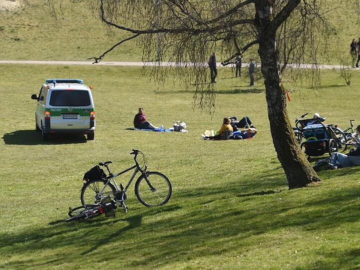 Ein Polizeibus fährt im Olympiapark bei schönstem Sonnenschein durch eine Grünfläche auf der sich Menschen tummeln. Foto: Felix Hörhager/dpa/Archivbild