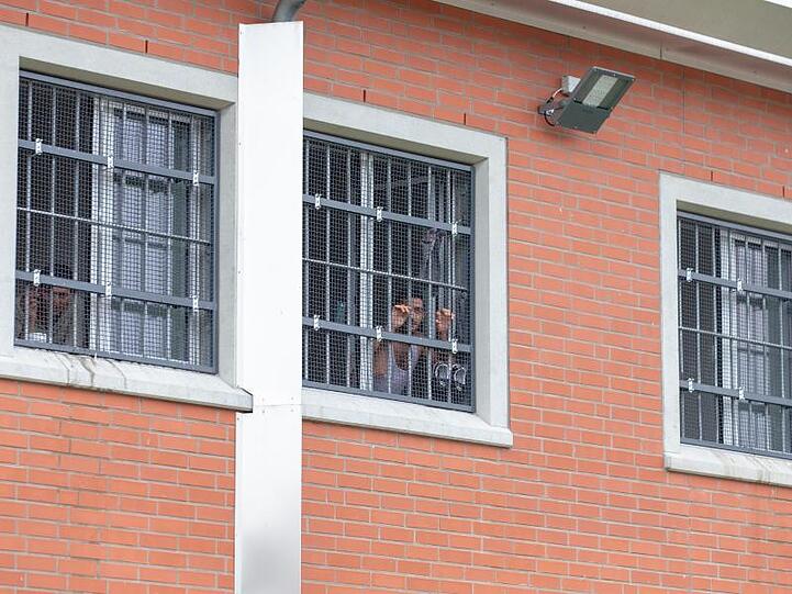 Unsassen blicken durch vergitterte Fenster in der Unterbringungseinrichtung für Ausreisepflichtige. Foto: Friso Gentsch/Archivbild
