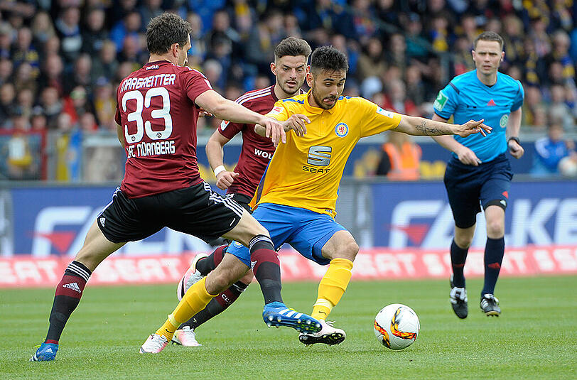 Braunschweigs Gerrit Holtmann (M.), Nürnbergs Georg Margreitter (l.) und Nürnbergs Tim Leibold (h.) kämpfen um den Ball.