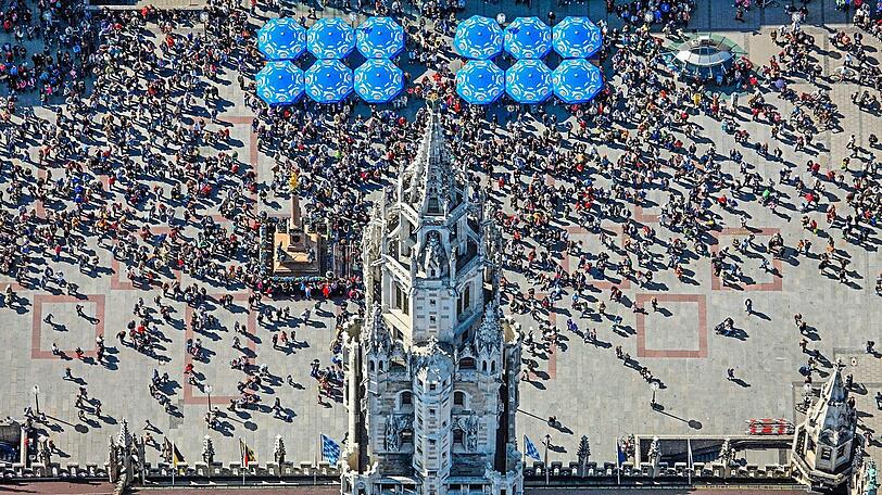 Blaue Schirme, hohe Türme und viele Menschen. So sieht man den Marienplatz selten.