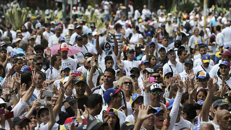 Menschen heben bei dem Schweigemarsch in Caracas die Hände. Trotz der Sperrung vieler Metrostationen und Zufahrtsstraßen hatten sich Tausende in der Hauptstadt versammelt.