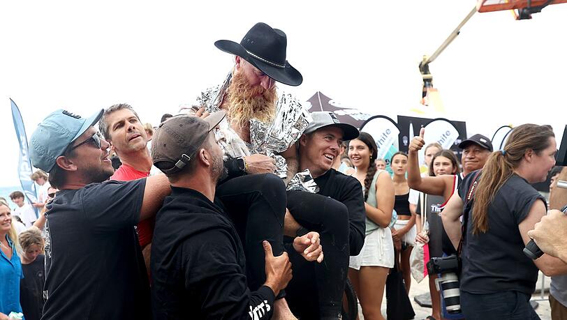 Der erschöpfte Blake Johnston wird von Freunden und Betreuern getragen, nachdem er den längsten Surf-Weltrekord von 500 Wellen in 40 Stunden vor der Küste Sydneys überboten hat.