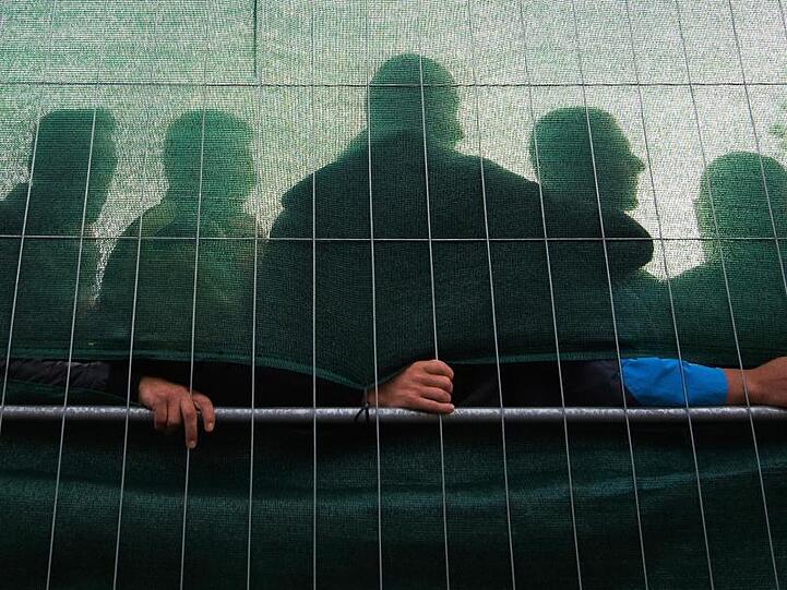 Flüchtlinge hinter dem Zaun einer Flüchtlingsunterkunft.