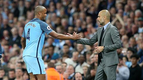 Manchesters Vincent Kompany und Trainer Pep Guardiola geben sich während des Spiels zur Auswechslung die Hand.
