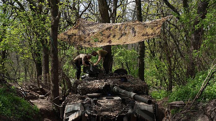 Ukrainische Soldaten installieren ein Maschinengewehr auf einem Panzer.