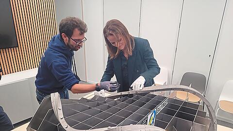 Proxima-Fusion-Magnetingenieur Nicolò Riva weist die Vorstandsvorsitzende des Startup-Verbands, Verena Pausder, in die Geheimnisse des neuentwickelten Hochtemperatur-Superleiters ein.