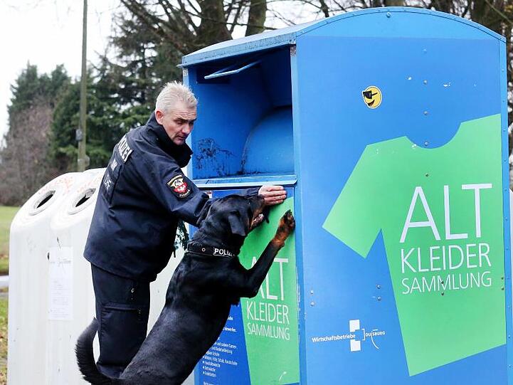 Polizeispürhund "Amigo" und sein Hundeführer suchen nach Spuren an einem Altkleidercontainer.