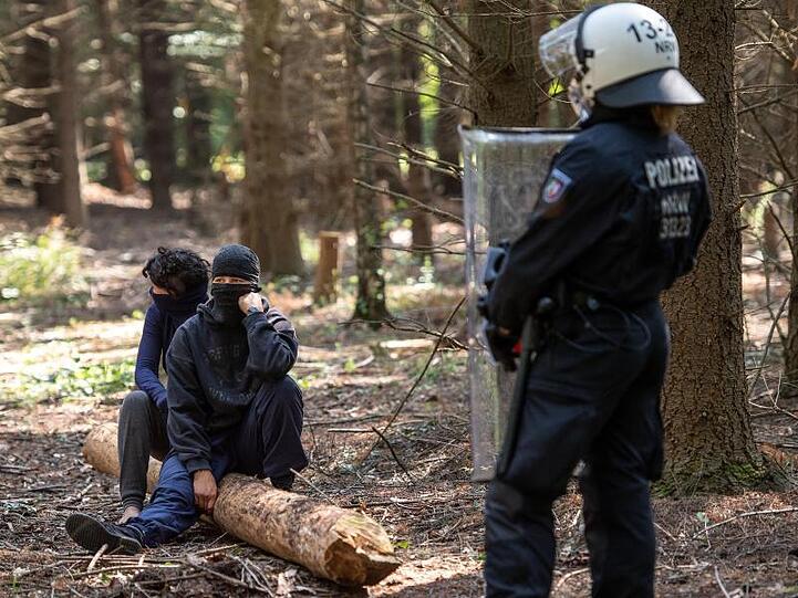 Ein Polizistin im Hambacher Wald vor zwei Umweltaktivisten.