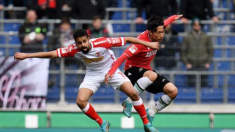 Sei Muroya (r) von Hannover und Sarpreet Singh von Regensburg kämpfen um den Ball.