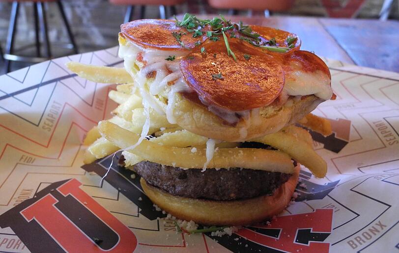 In der Bar "Clinton Hall" in New York (USA) müssen sich Gäste jetzt nicht mehr zwischen Pizza, Pommes und Burger entscheiden. Stattdessen können sie seit Kurzem den Pizza-Pommes-Burger bestellen.
