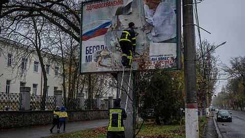 Feuerwehrleute entfernen russische Plakate in Cherson.