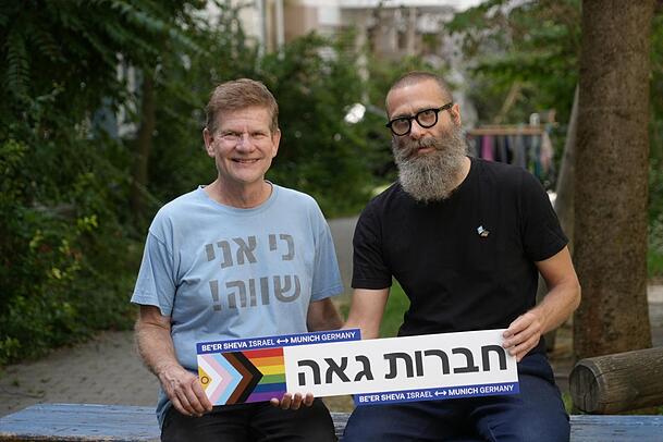 Wolfgang Scheel (l.) und Frank Zuber. Der Schriftzug auf dem Schild ist hebräisch und bedeutet "Stolze Freundschaft" - stolz im Sinne des stolzen Umgangs mit der eigenen sexuellen Identität. Auf Wolfgang Scheels T-Shirt steht "Ich bin gleich" im Sinne von "gleichwertig". Wolfgang Scheel (l.) und Frank Zuber. Der Schriftzug auf dem Schild ist hebräisch und bedeutet "Stolze Freundschaft" - stolz im Sinne des stolzen Umgangs mit der eigenen sexuellen Identität. Auf Wolfgang Scheels T-Shirt steht "Ich bin gleich" im Sinne von "gleichwertig".