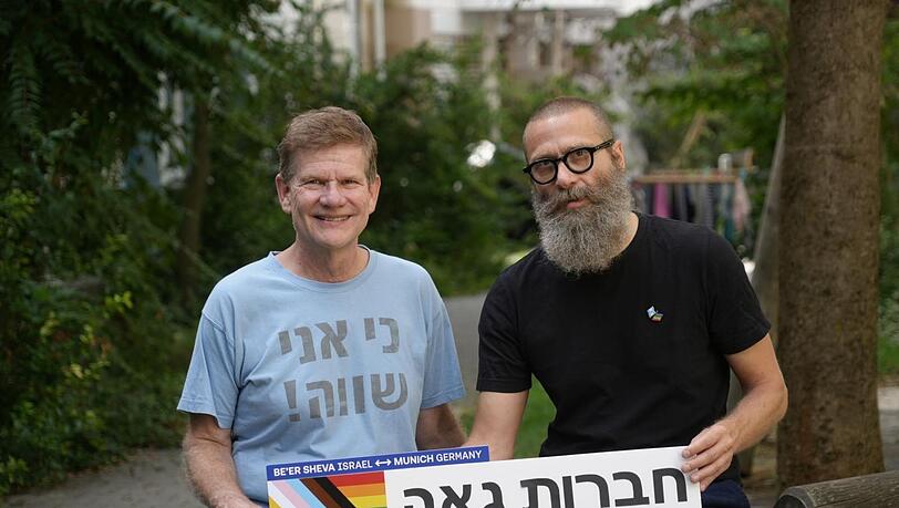 Wolfgang Scheel (l.) und Frank Zuber. Der Schriftzug auf dem Schild ist hebräisch und bedeutet "Stolze Freundschaft" - stolz im Sinne des stolzen Umgangs mit der eigenen sexuellen Identität. Auf Wolfgang Scheels T-Shirt steht "Ich bin gleich" im Sinne von "gleichwertig". Wolfgang Scheel (l.) und Frank Zuber. Der Schriftzug auf dem Schild ist hebräisch und bedeutet "Stolze Freundschaft" - stolz im Sinne des stolzen Umgangs mit der eigenen sexuellen Identität. Auf Wolfgang Scheels T-Shirt steht "Ich bin gleich" im Sinne von "gleichwertig".