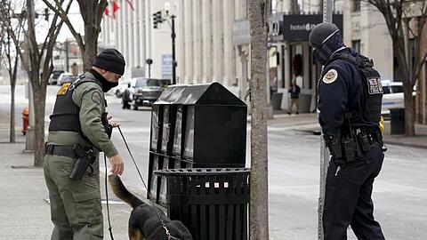 Ein Mitarbeiter der Hundestaffel (K9) sucht das Gebiet mit Bombenspürhunden ab, um mögliche weitere Explosionen auszuschließen.