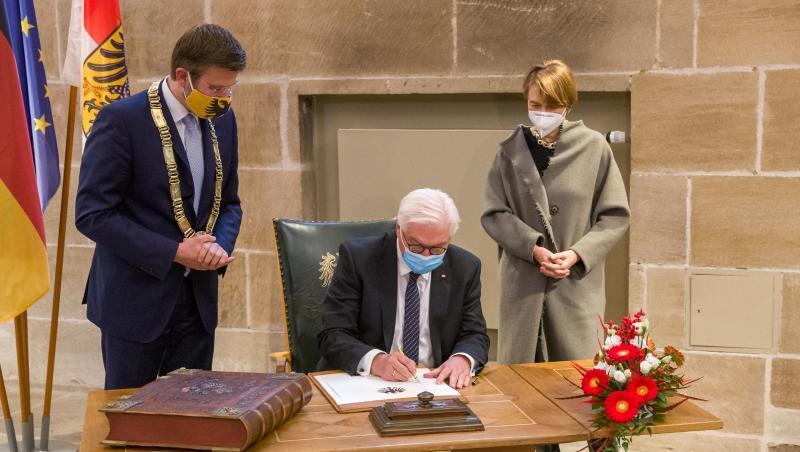 Bundespräsident Frank-Walter Steinmeier (M) trägt sich im Rathaus ins Goldene Buch ein.