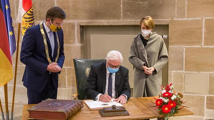 Bundespräsident Frank-Walter Steinmeier (M) trägt sich im Rathaus ins Goldene Buch ein.