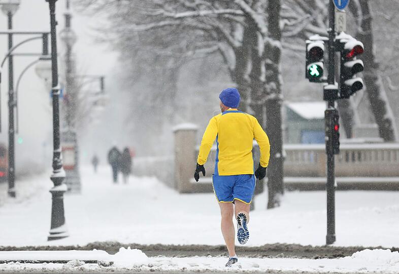 Ein Jogger läuft in kurzer Hose am 19.3. durch das komplett verschneite Berlin.