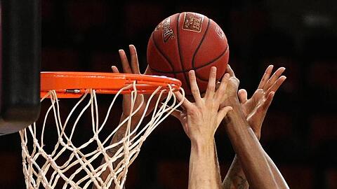 Spieler zweier Basketballmannschaften im Kampf um den Ball.