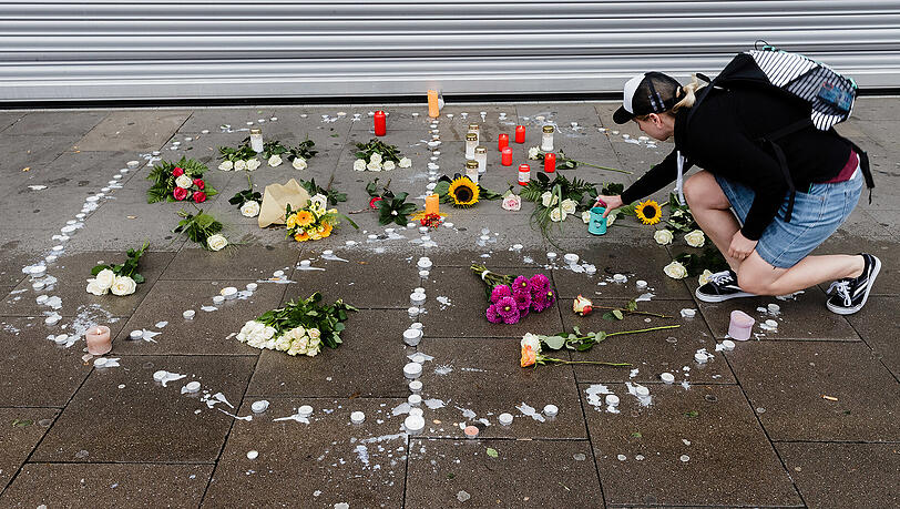 Passanten legen Blumen und Kerzen vor dem Supermarkt ab. Passanten legen Blumen und Kerzen vor dem Supermarkt ab.