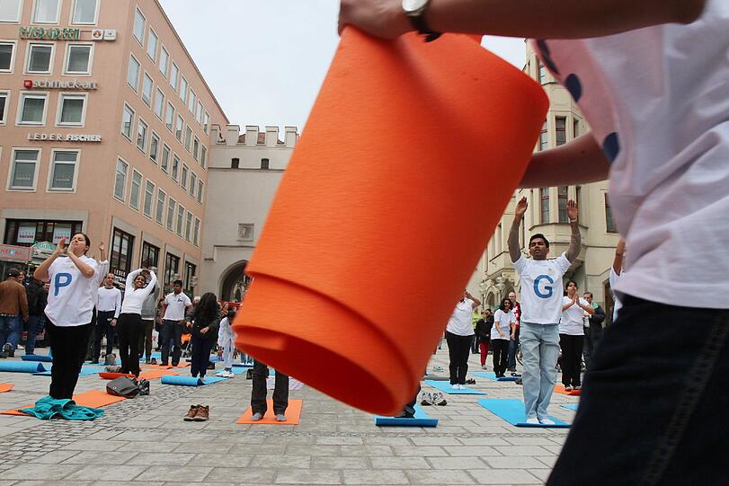 Hopsen und Dehnen in der Fußgängerzone: Am Stachus haben sich Yoga-Fans zu einem Flashmob unter freiem Himmel verabredet. Die Bilder.