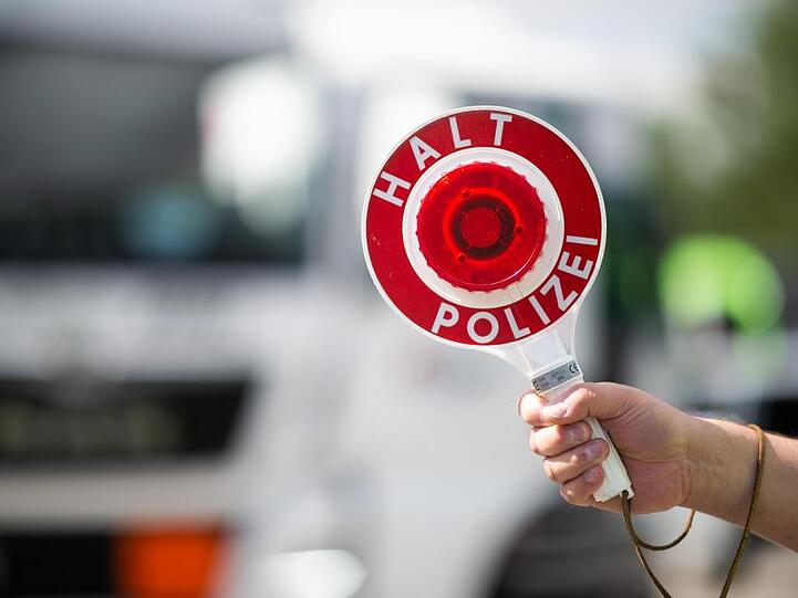 Ein Polizist hält eine Polizeikelle mit der Aufschrift "Halt Polizei". Foto: Jonas Güttler/dpa/Archivbild