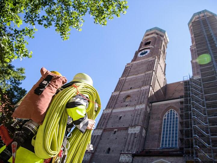 Ein Feuerwehrmann steht mit einem Schlauch vor der Frauenkirche. Foto: Matthias Balk