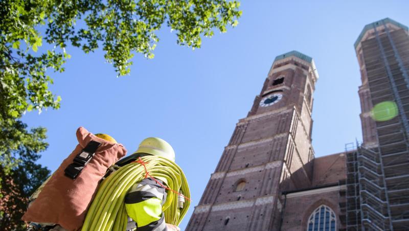 Ein Feuerwehrmann steht mit einem Schlauch vor der Frauenkirche. Foto: Matthias Balk Ein Feuerwehrmann steht mit einem Schlauch vor der Frauenkirche. Foto: Matthias Balk