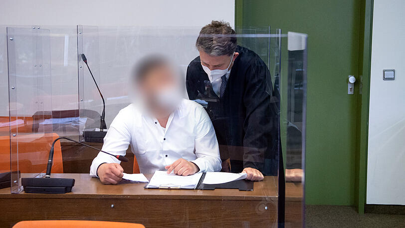 Der angeklagte Mann unterhält sich vor Prozessbeginn mit seinem Anwalt.