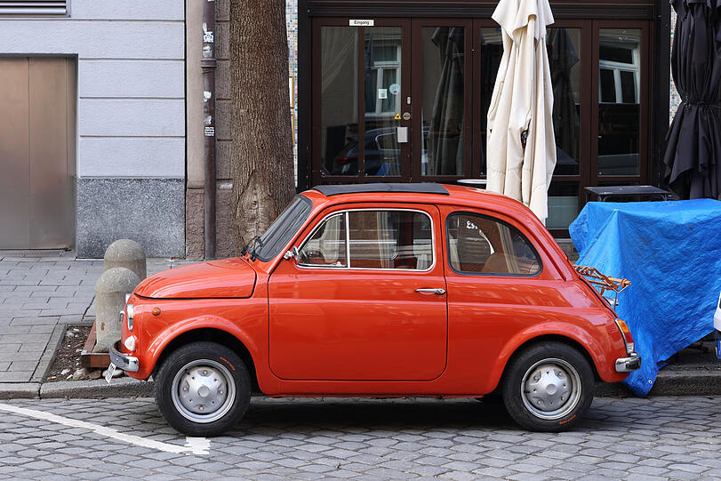 Hingucker am Straßenrand: ein uralter Fiat 500 in Knallrot.
