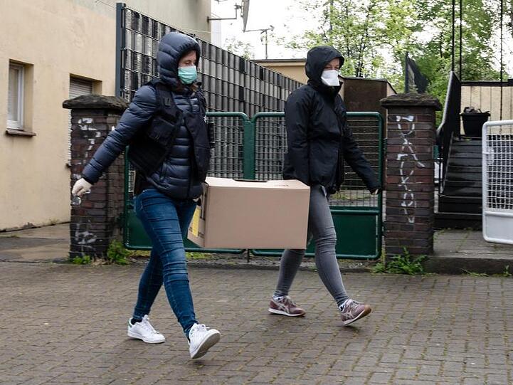 Polizistinnen tragen einen Karton mit Beweismitteln aus den Räumen der Gemeinschaft Libanesischer Emigranten in Dortmund.