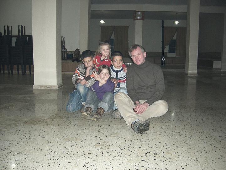 Hilfe vor Ort: Der Münchner Kabarettist Christian "Fonsi" Springer (r.) mit vier Kindern, die in einem dunklen Gebäude an der libanesischen Grenze untergekommen sind.