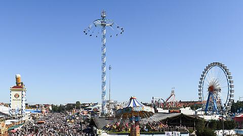 Besucher und Besucherinnen gehen über das Gelände der Wiesn.