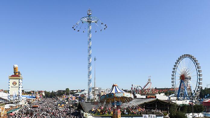 Besucher und Besucherinnen gehen über das Gelände der Wiesn.