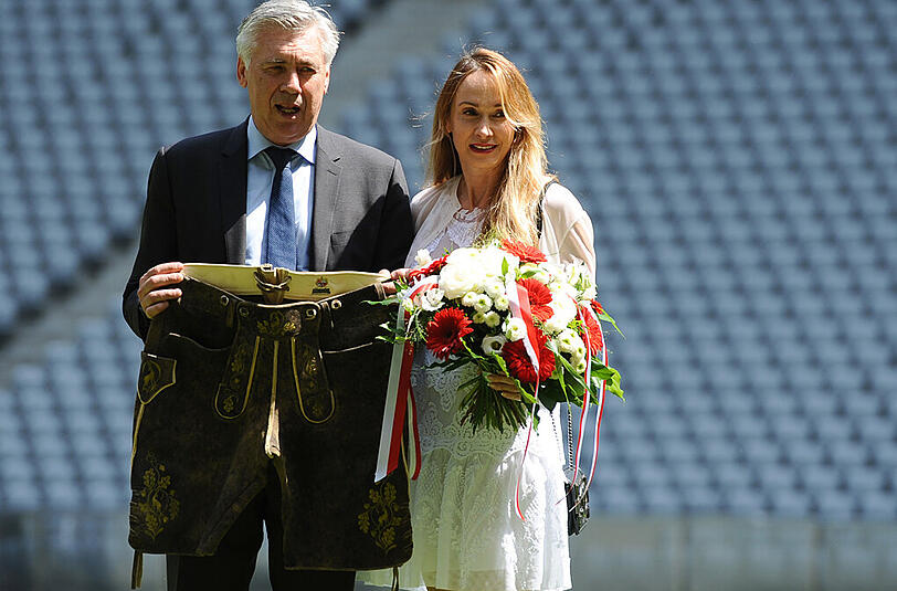 So, damit ist er ein Bayer: Stolz hält Carlo Ancelotti eine Lederhose in die Kameras. Für die Frau an seiner Seite gab es Blumen - immerhin.