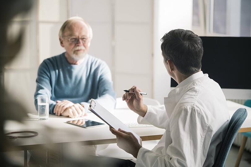 Ein Mann spricht mit seinem Doktor. Der Hausarzt sollte mit ins Boot geholt werden, wenn man eine Patientenverfügung verfassen möchte.