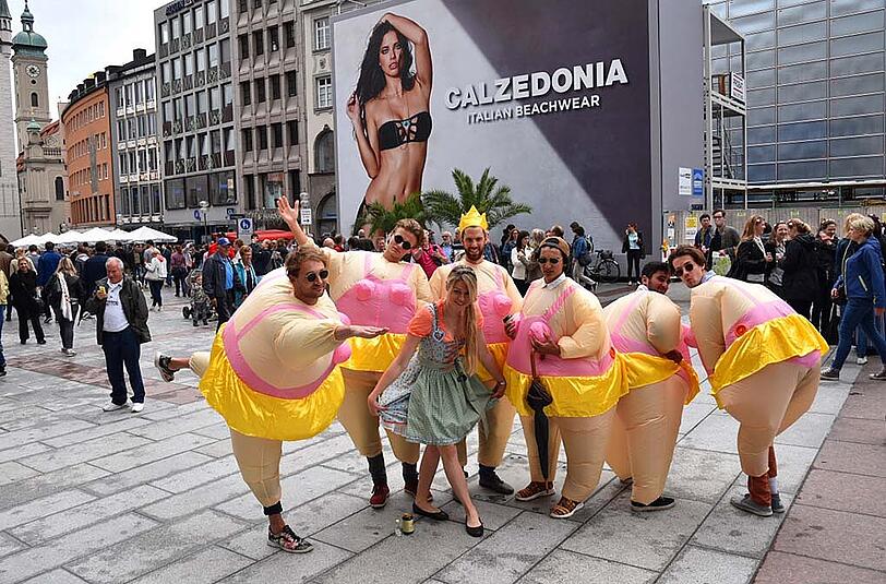 Am Ende werden sie zum Fotomotiv: Passanten scharen sich um die Junggesellen, die sich vor der Calzedonia-Werbung am Marienplatz prächtig amüsieren.